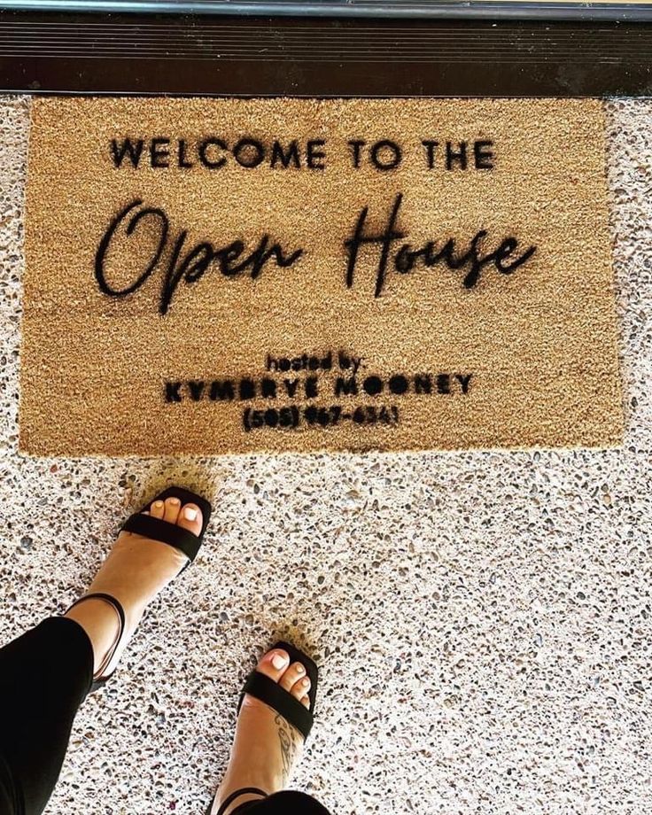 a person standing in front of a welcome mat that says, welcome to the open house