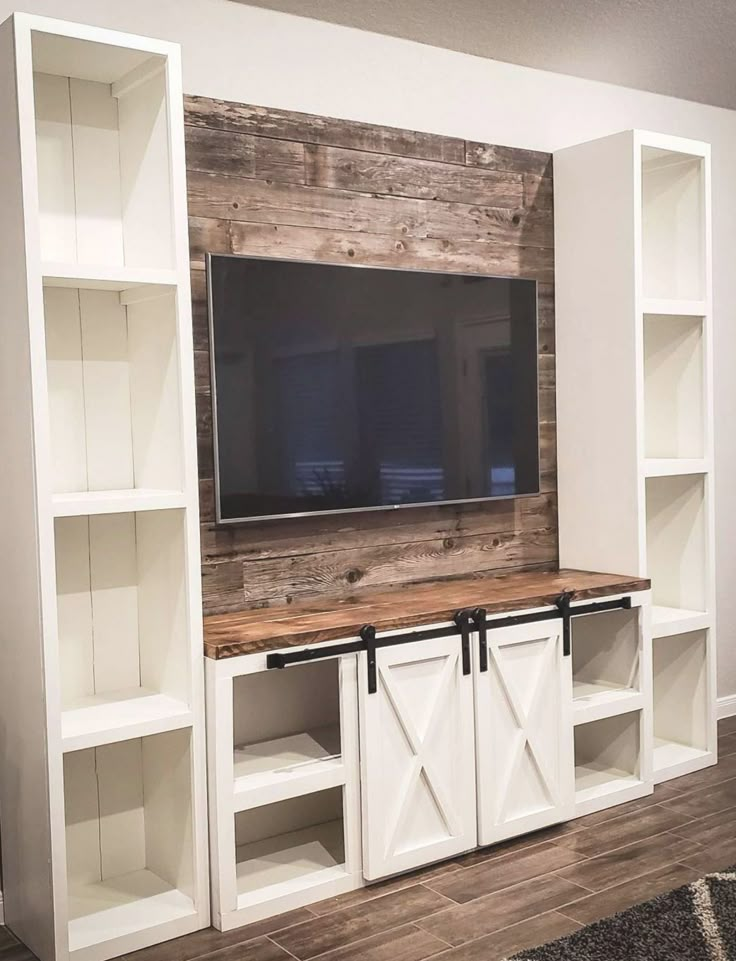 the entertainment center is made out of white bookcases with sliding doors and a barn door