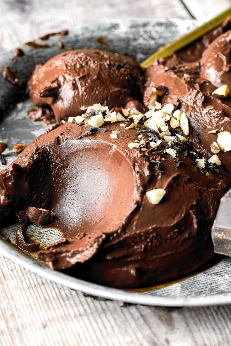 chocolate ice cream in a bowl with spoons on the side and chopped almonds on top