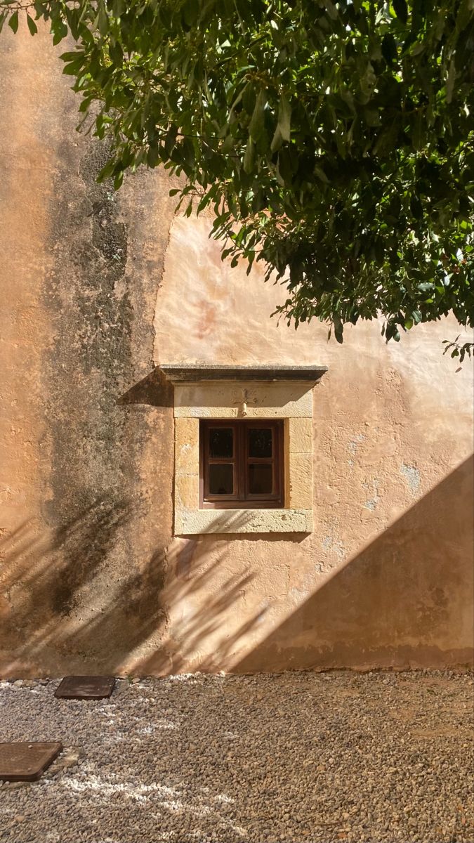 a window in the side of a building with a tree next to it on a sunny day