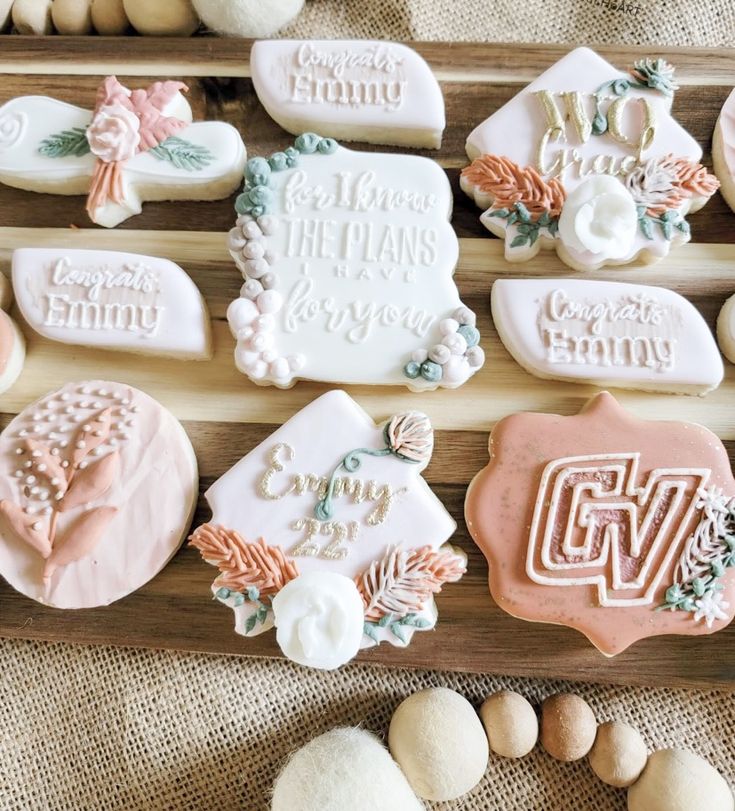 decorated cookies are arranged on a wooden tray with shells and stones around them, along with the words congratulations written in cursive writing