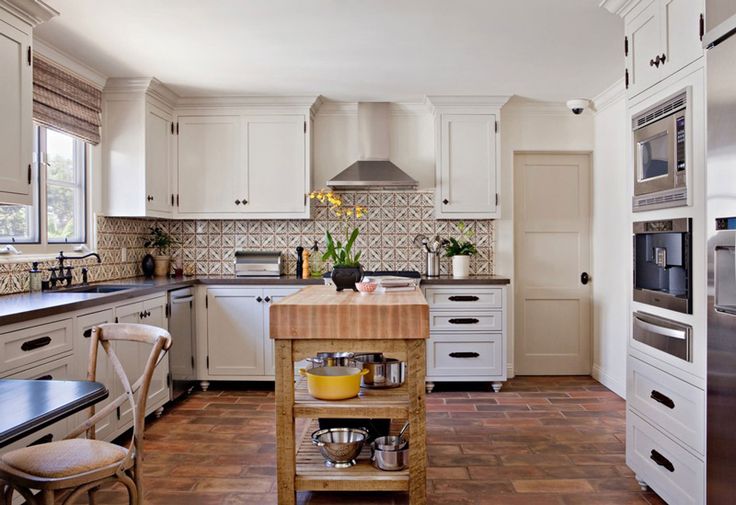 a kitchen with white cabinets and wooden island in front of the stove top ovens