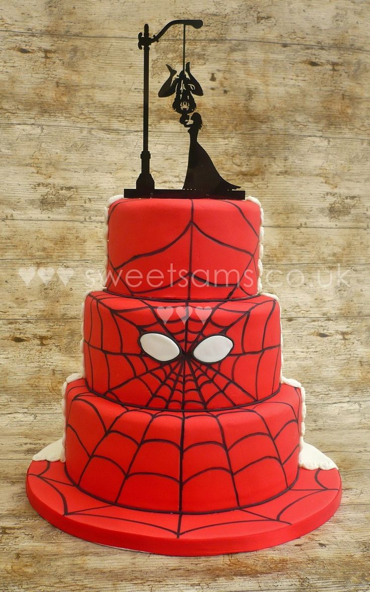 a three tiered cake with a spiderman face on top