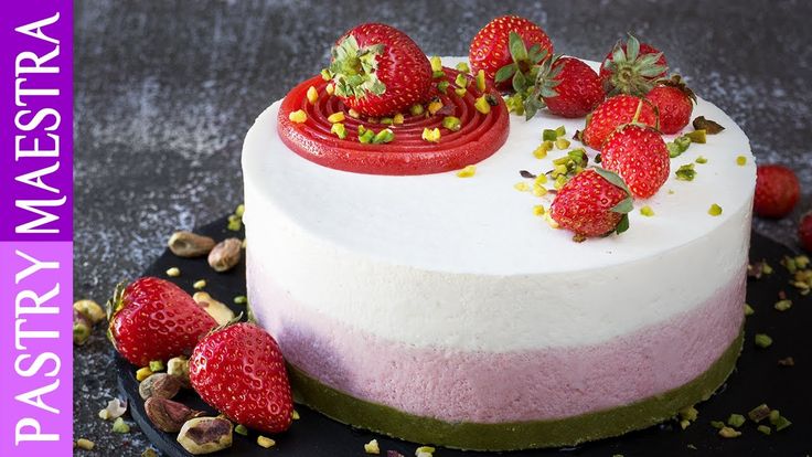 a white cake with strawberries on top and nuts around the edges, sitting on a black plate