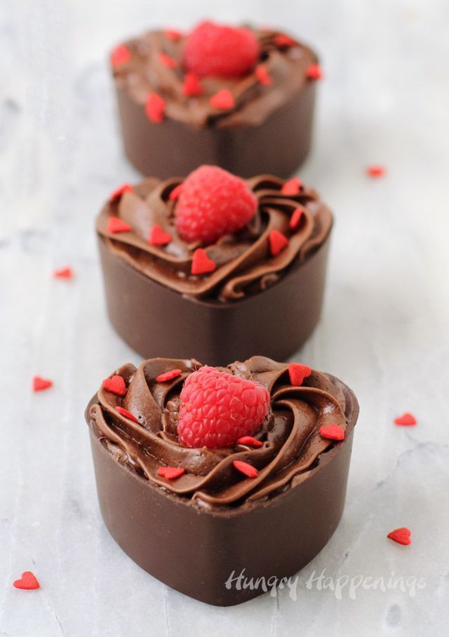 three heart shaped cakes with chocolate frosting and raspberries