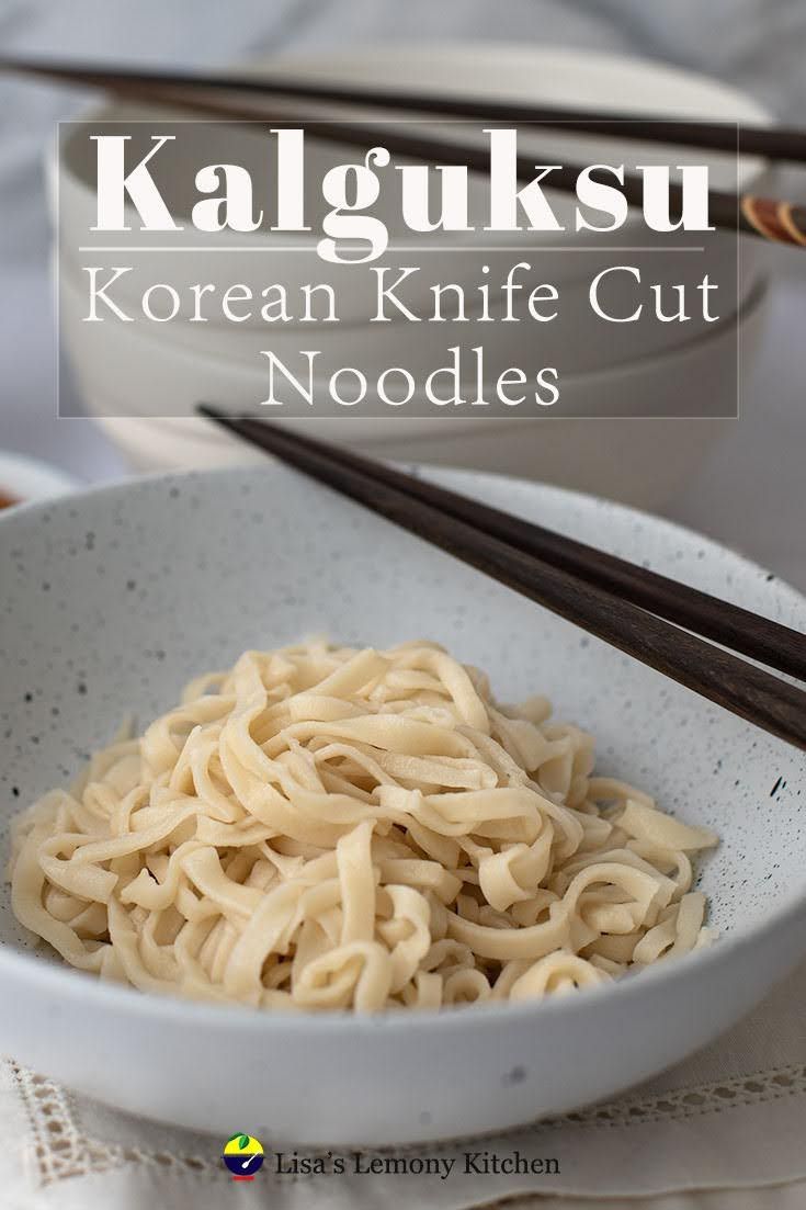 a bowl filled with noodles and chopsticks on top of a white table cloth