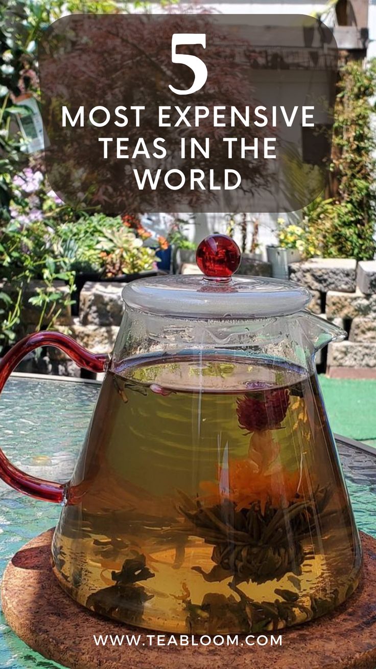 a glass tea pot filled with green tea sitting on top of a wooden table