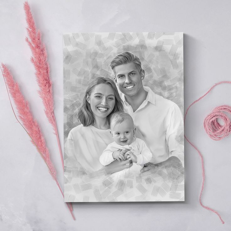 a black and white photo of a couple holding a baby with pink yarn next to it