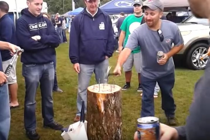 several men standing around a tree stump with cans in their hands and one man holding a beer