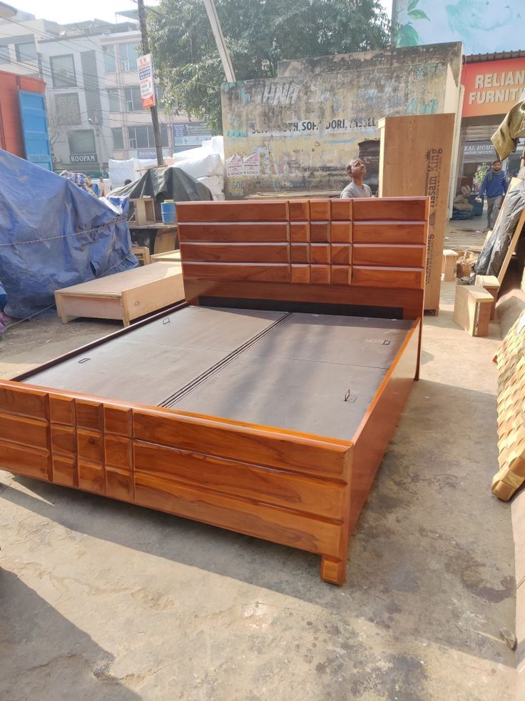 a wooden bed frame sitting on top of a cement floor next to a pile of boxes