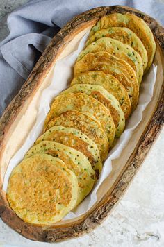 a wooden platter filled with sliced up food on top of a white table cloth