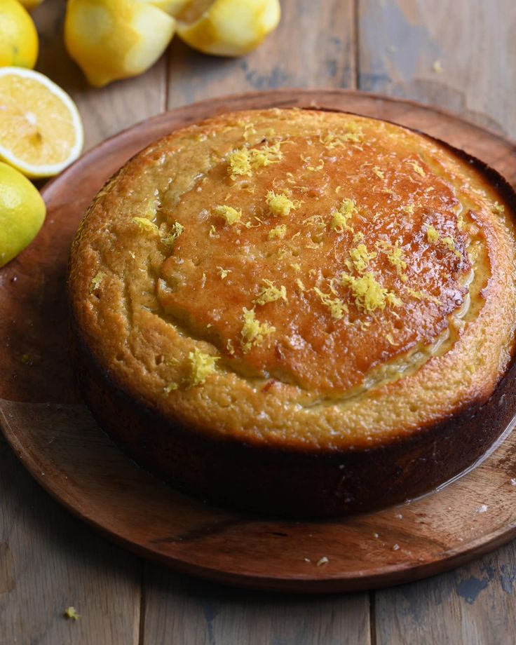 a cake sitting on top of a wooden plate next to lemons