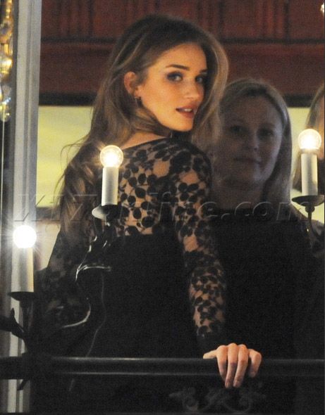 a woman in black dress standing next to candles