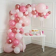 pink and white balloons are hanging from the ceiling in a room with wood flooring