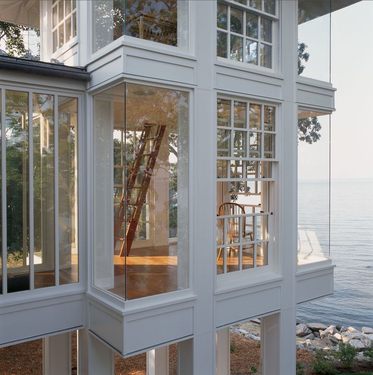 the inside of a white house with windows and stairs leading up to the water's edge