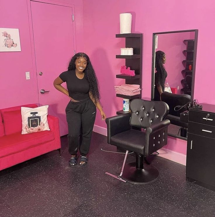 a woman standing next to a chair in a room with pink walls and black furniture