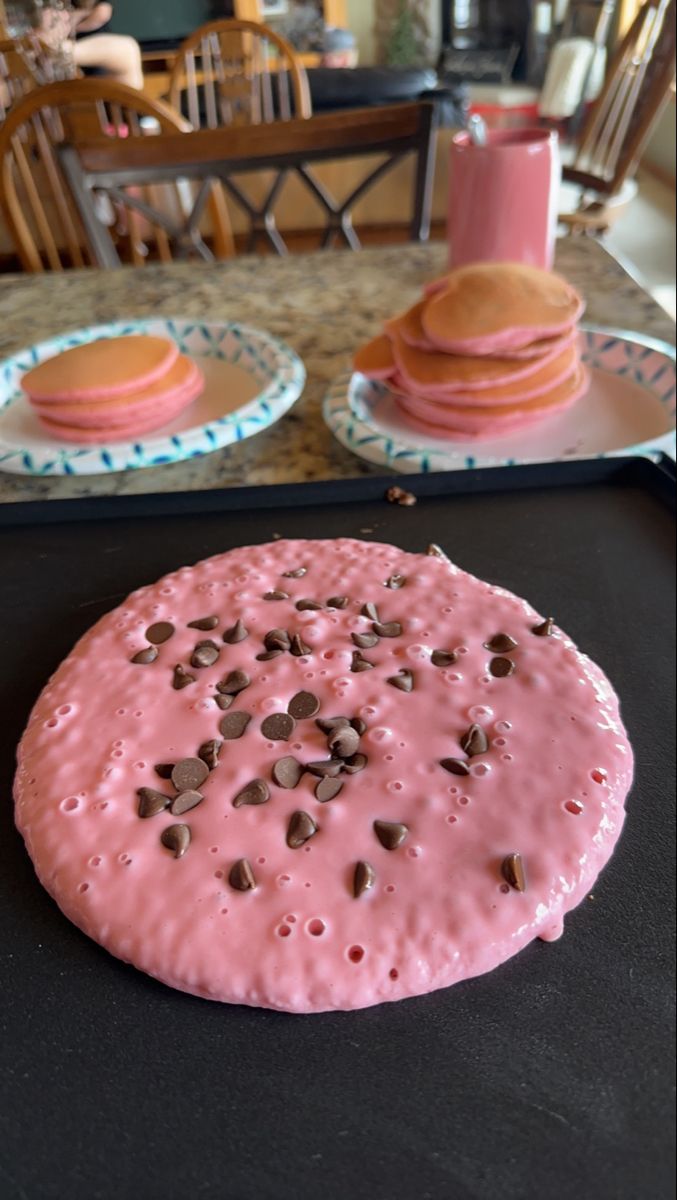 pink frosted doughnut with chocolate chips on it sitting on top of a table