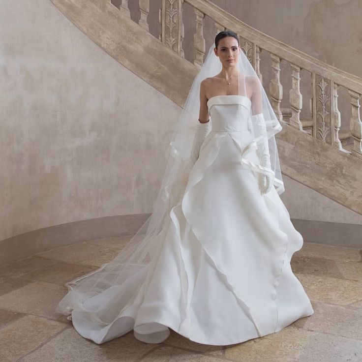 a woman in a white wedding dress standing next to a staircase