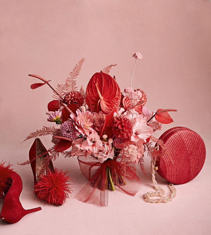 a bouquet of flowers and shoes on a pink background