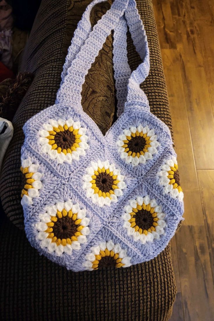 a crocheted sunflower purse sitting on top of a couch next to a pillow