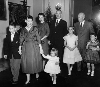 an old black and white photo of people holding hands with two children in front of them