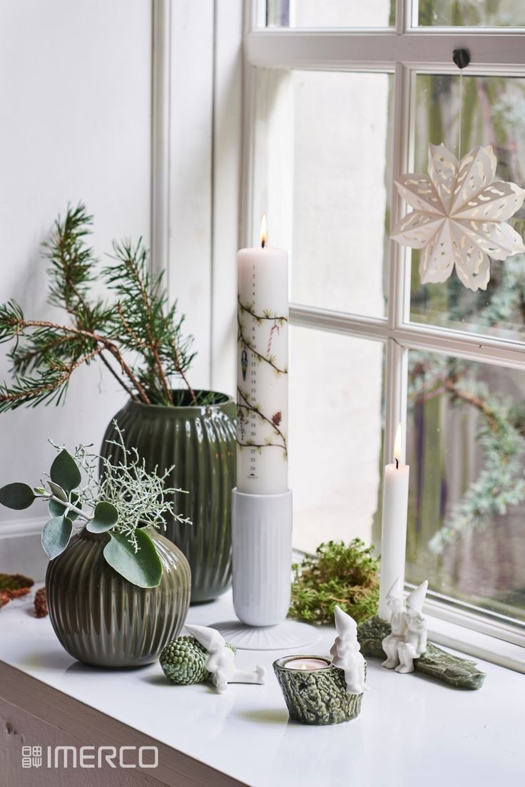 two vases with plants and candles on a window sill