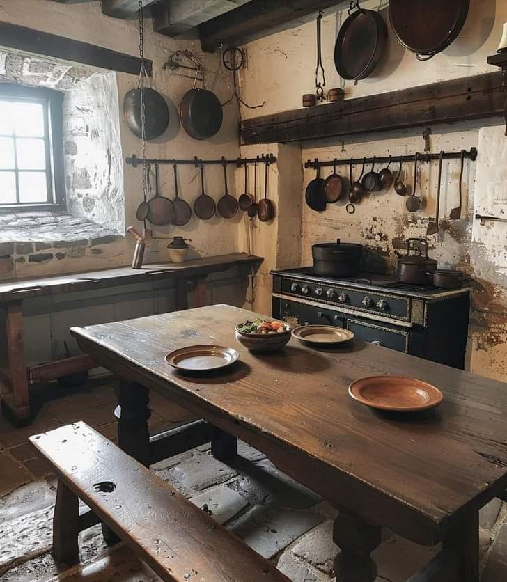 an old fashioned kitchen with wooden table and benches in front of the stove, pots and pans hanging on the wall