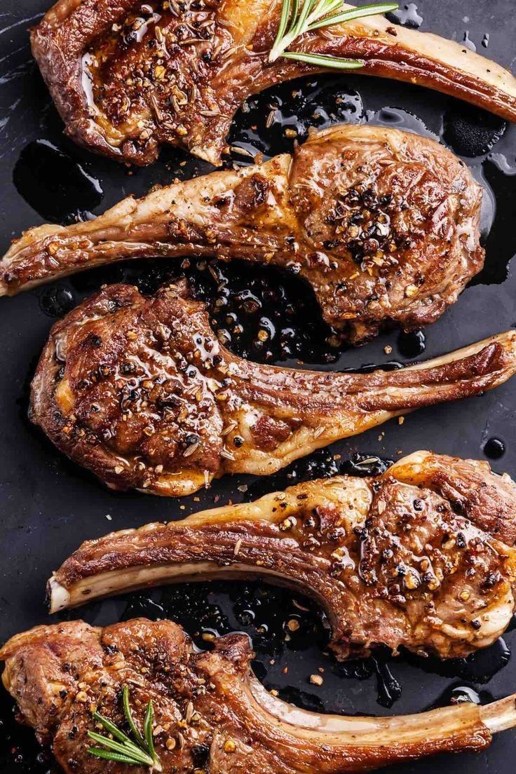 two steaks on a black plate with rosemary sprigs