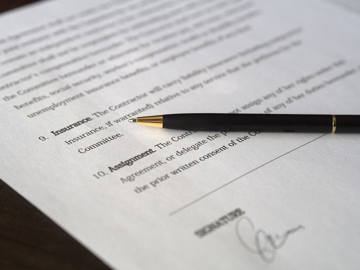 a pen sitting on top of a piece of paper next to a document with writing