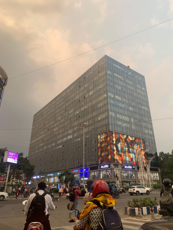 people are riding motorcycles in front of a large building with many windows on the side