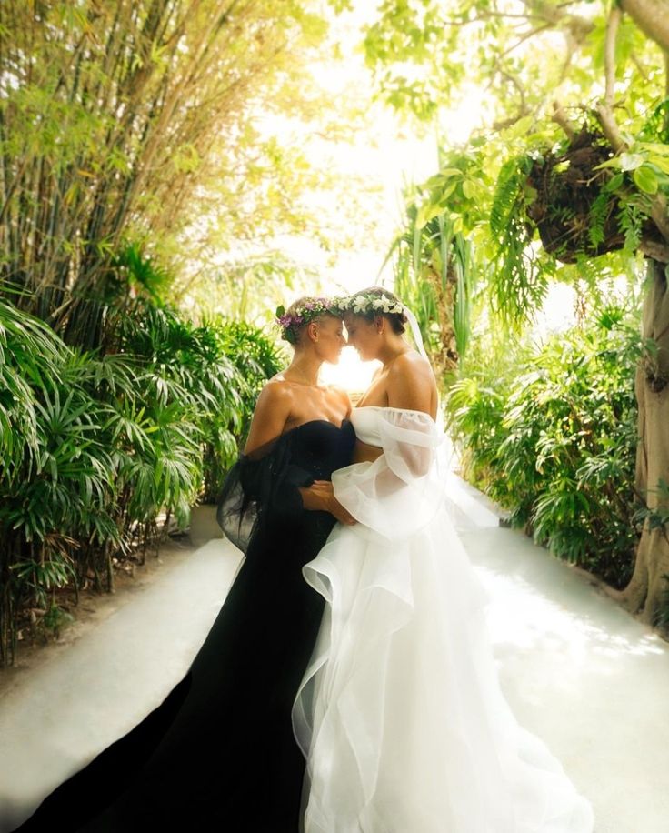 two women in black and white gowns standing next to each other on a path