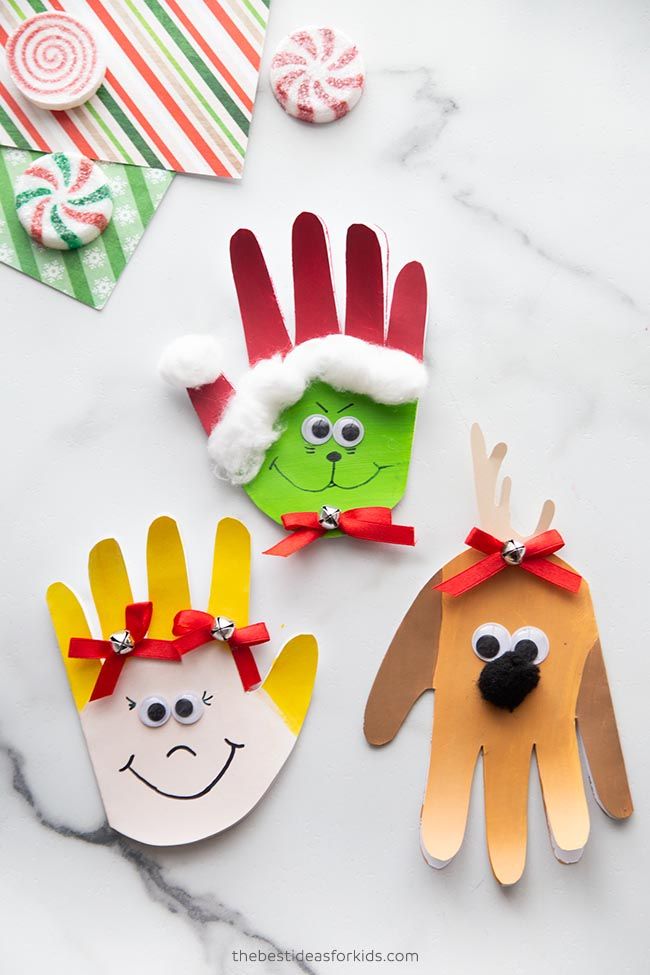 three handprinted christmas cards on a marble surface with candy canes and candies in the background