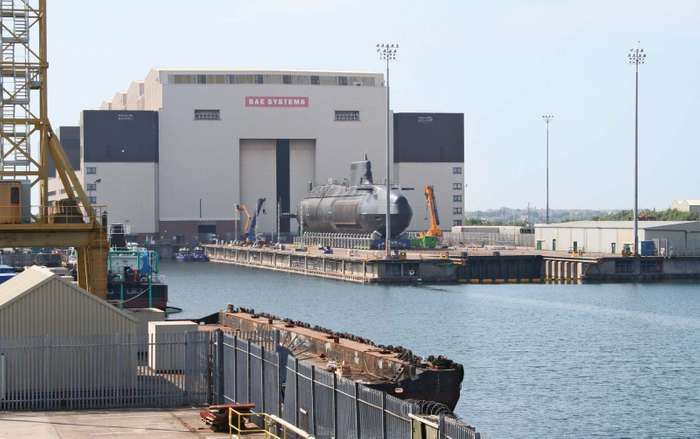 a large boat is docked in the water near some buildings and other structures that are behind it