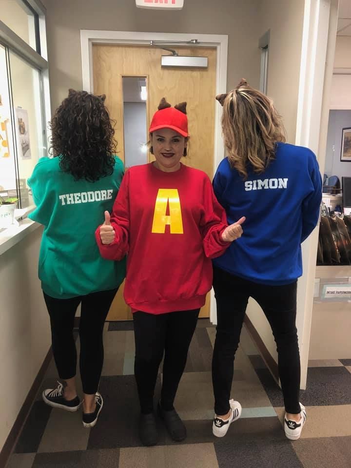 three women in matching sweatshirts are posing for the camera while one woman is wearing a mcdonald's costume