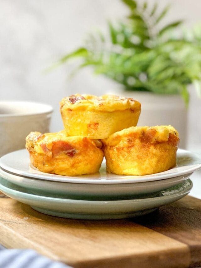 three mini quiche cups on a plate next to a cup of coffee and a potted plant