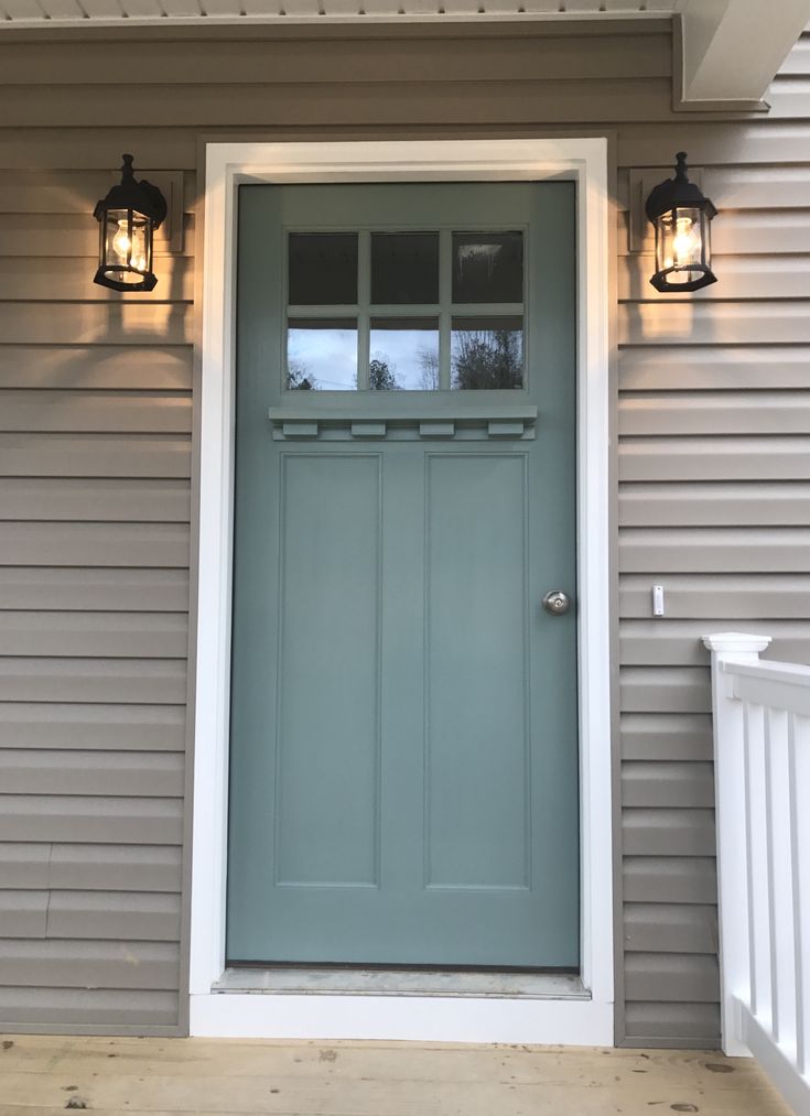 the front door of a house with two lights on each side and an open window