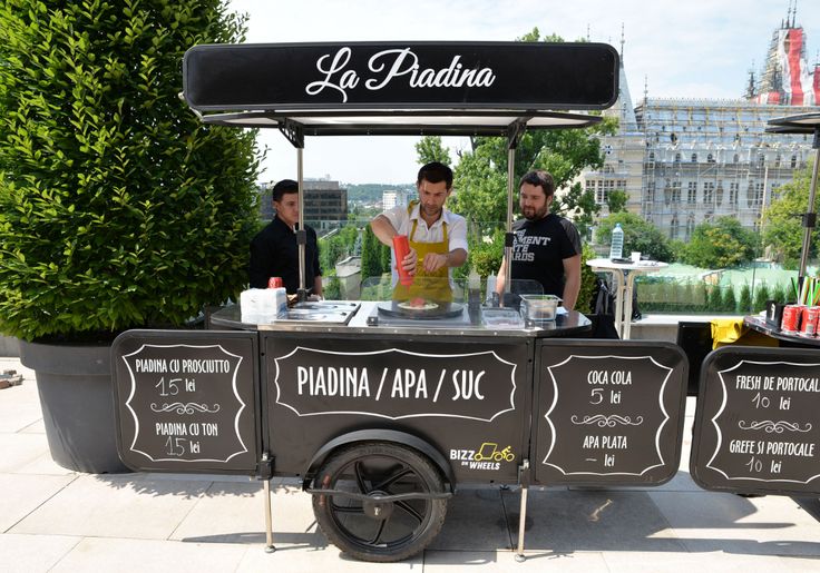 three men are behind a food cart with drinks on the table in front of them