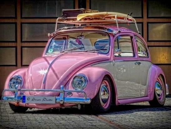 a pink vw bug parked in front of a building with surfboards on top