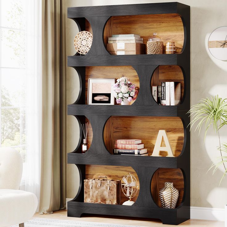 a book shelf filled with lots of books and other items next to a white chair