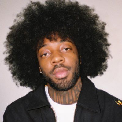 a man with an afro and piercings on his face is looking at the camera