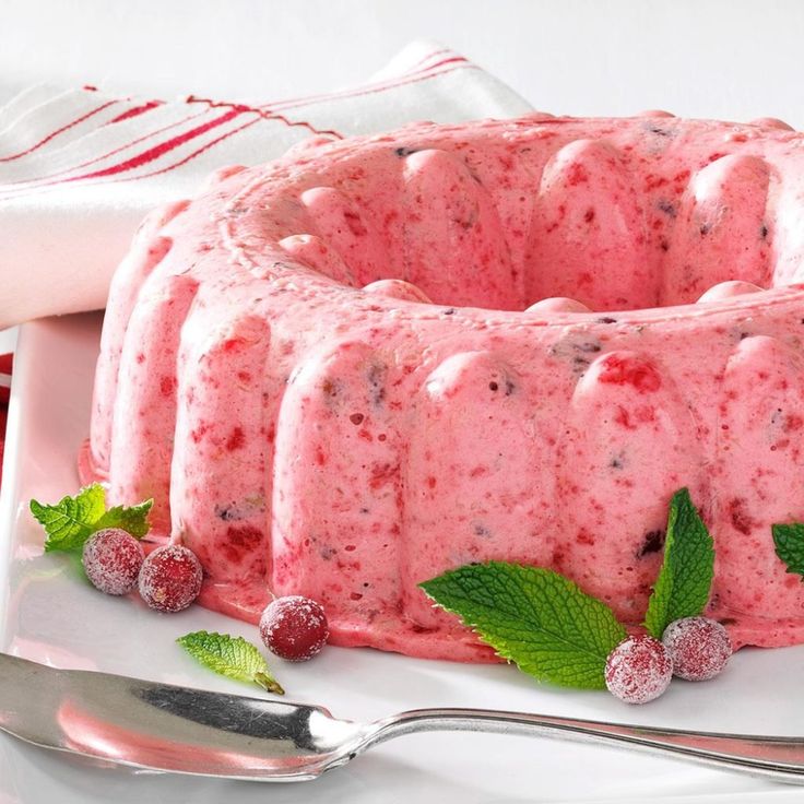 a bundt cake with raspberries and mints on the side next to a fork