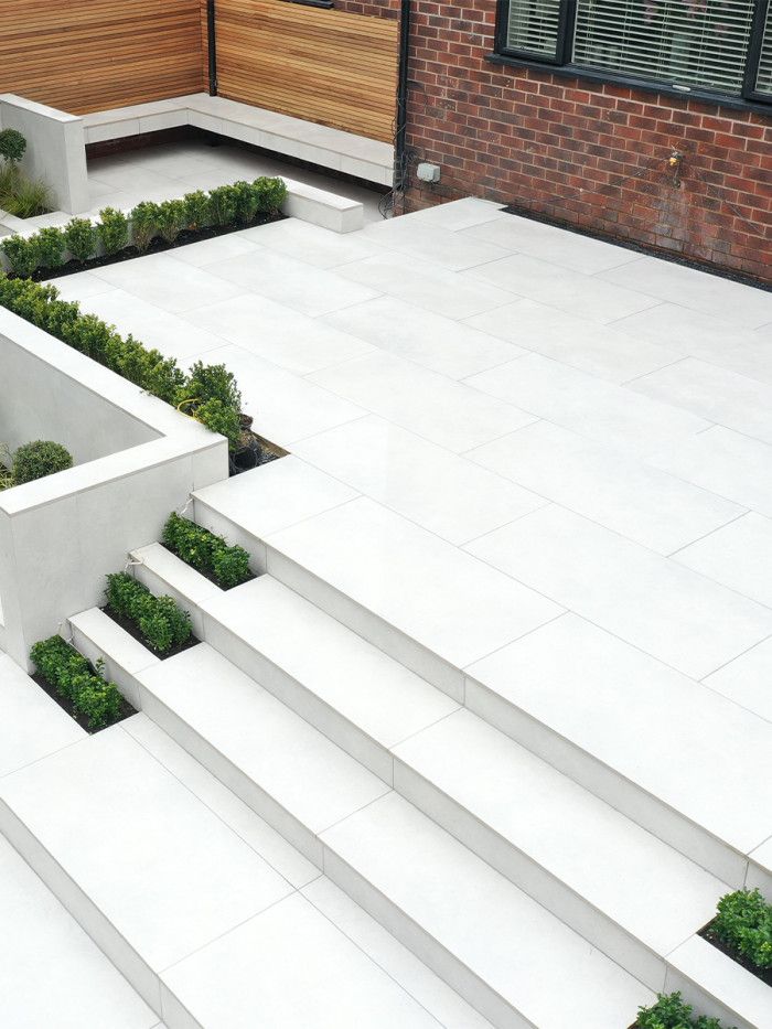 modern garden design with white concrete steps and planters on the side of a building