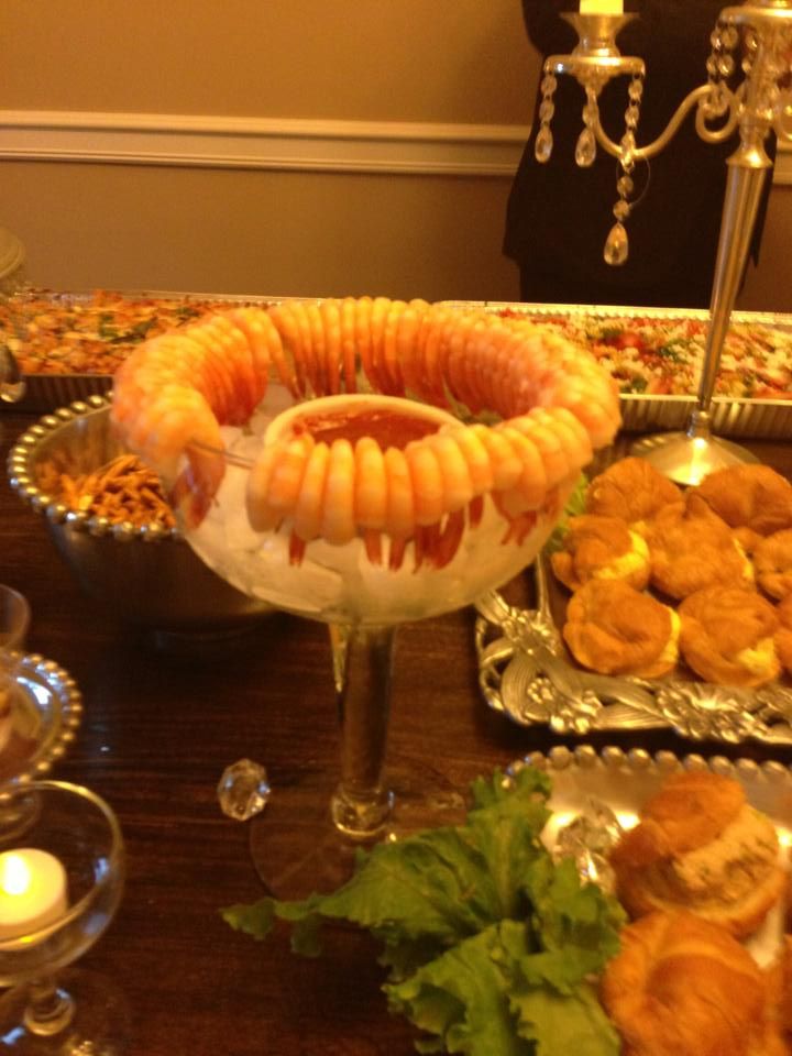 an assortment of food is displayed on a table with silver dishes and candles in the background