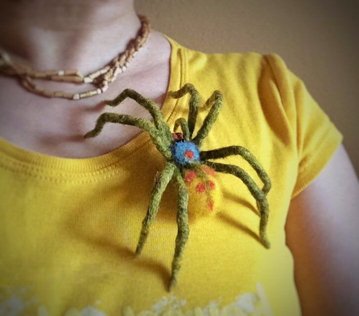 a close up of a person wearing a yellow shirt with a spider on it