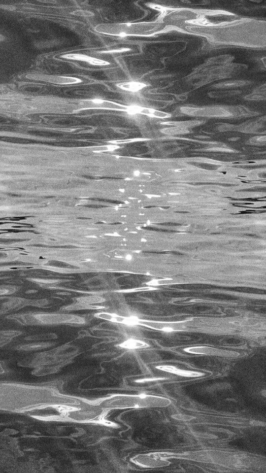 black and white photograph of water with sun reflecting on it