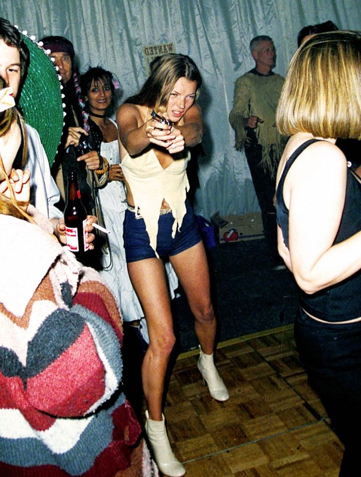 people are dancing and having fun at a party with drinks in their hands, one woman is holding a wine bottle