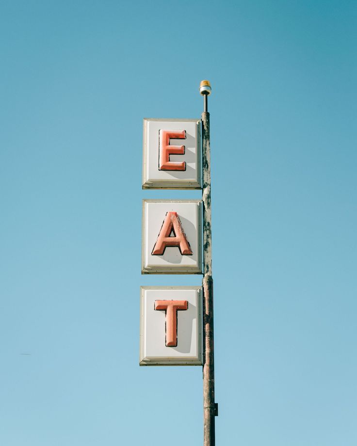 a sign that says eat at on the side of a building with blue sky in the background