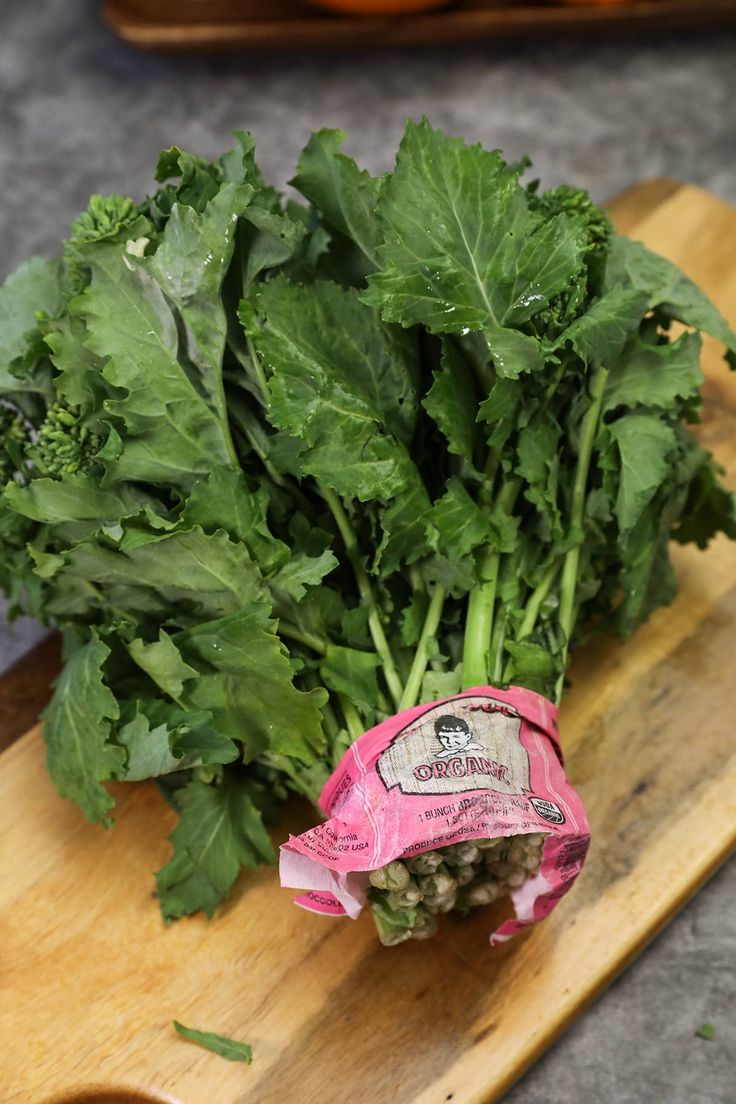 a bunch of green leafy vegetables on a cutting board with a pink wrapper