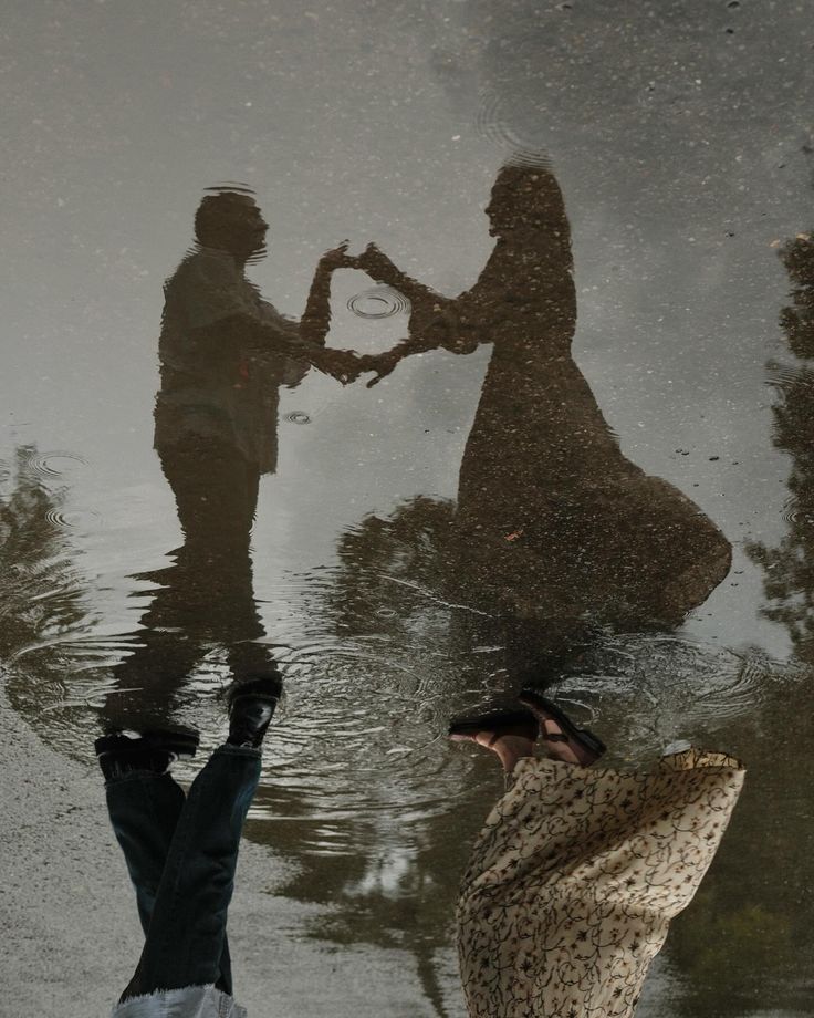 two people are standing in the water and one is holding hands with another person's reflection