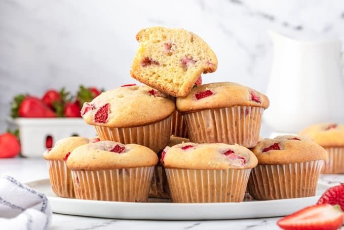 strawberry muffins stacked on top of each other with strawberries in the background